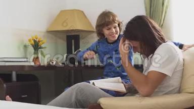 两个哥哥坐在扶手椅上，哥哥给弟弟读了一本书，小男孩摸着哥哥的长发